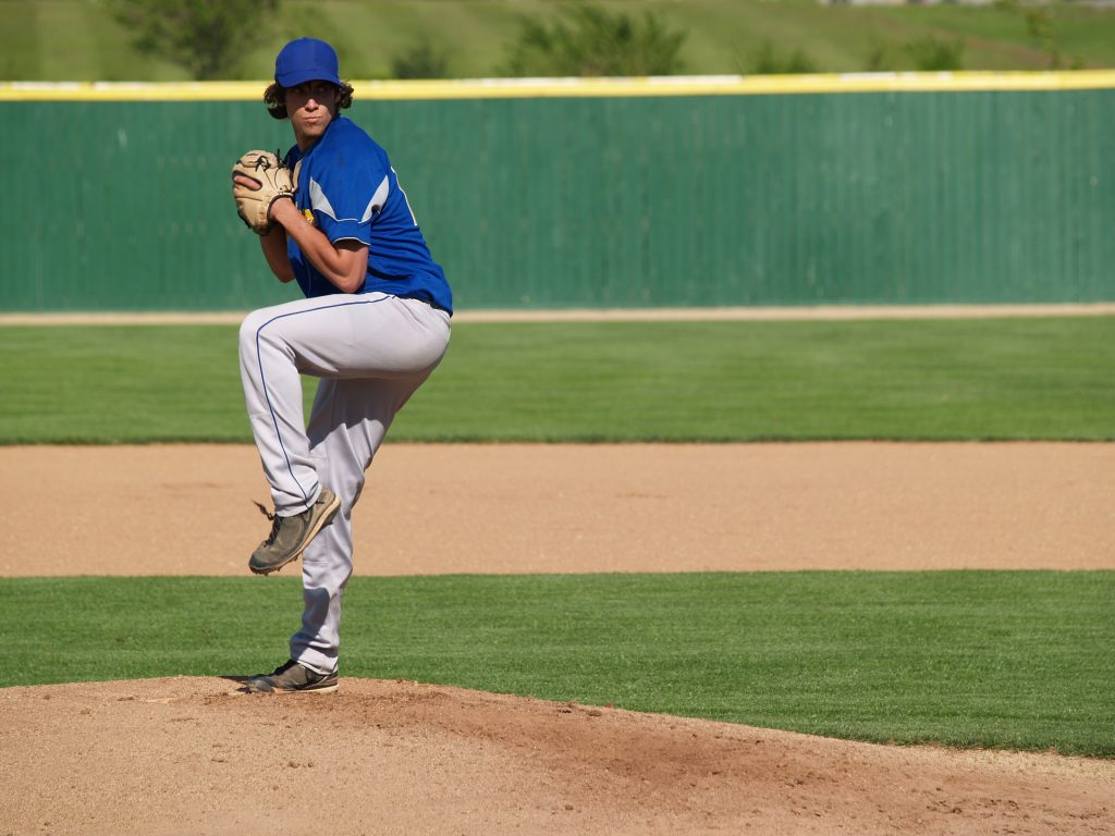 action shot of a high school baseball pitcher winding up to throw the baseball